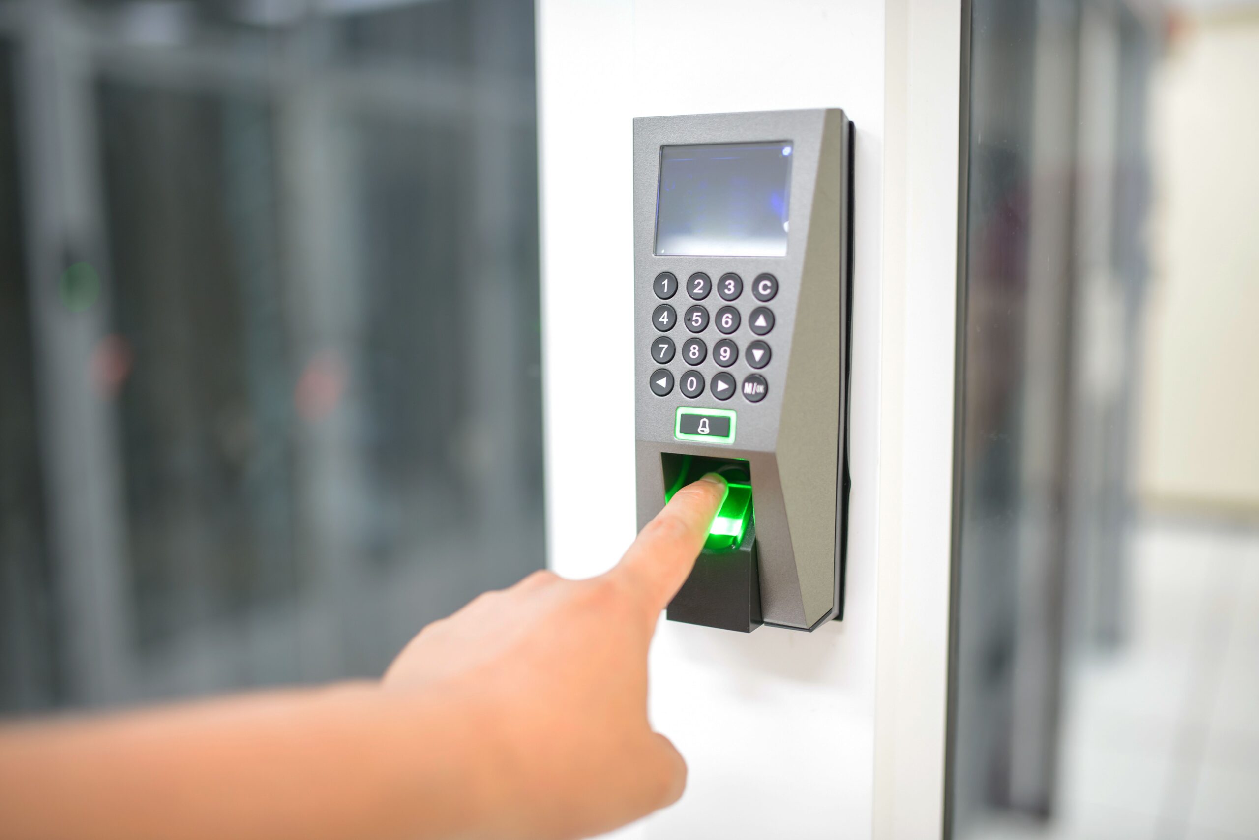 Person using a fingerprint scanner for secure entry, representing a biometric authentication system Singapore worksites use