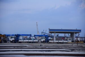 Industrial shipping yard with cranes and trucks where a vehicle speed detection system can monitor site traffic