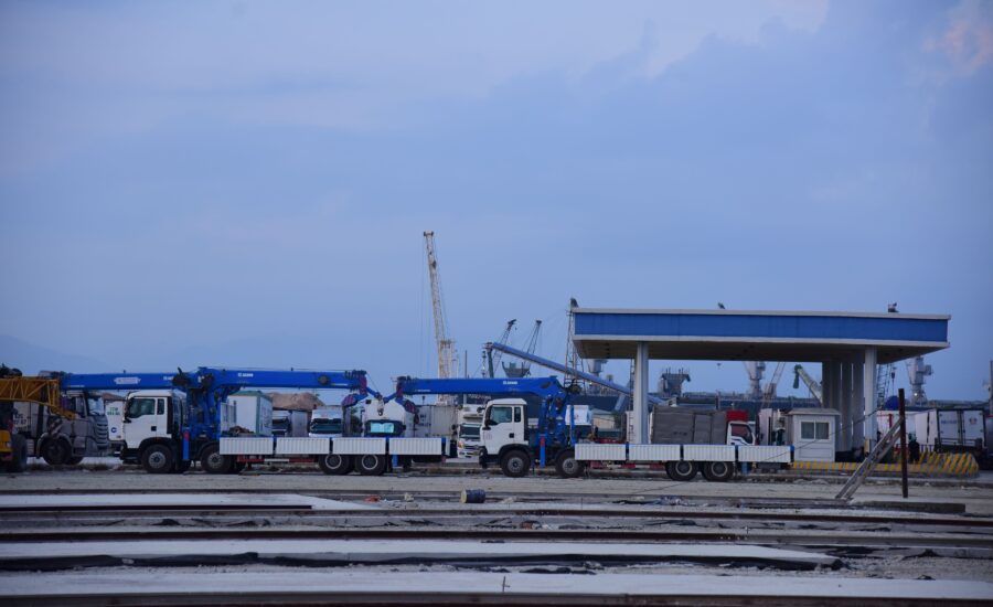 Industrial shipping yard with cranes and trucks where a vehicle speed detection system can monitor site traffic