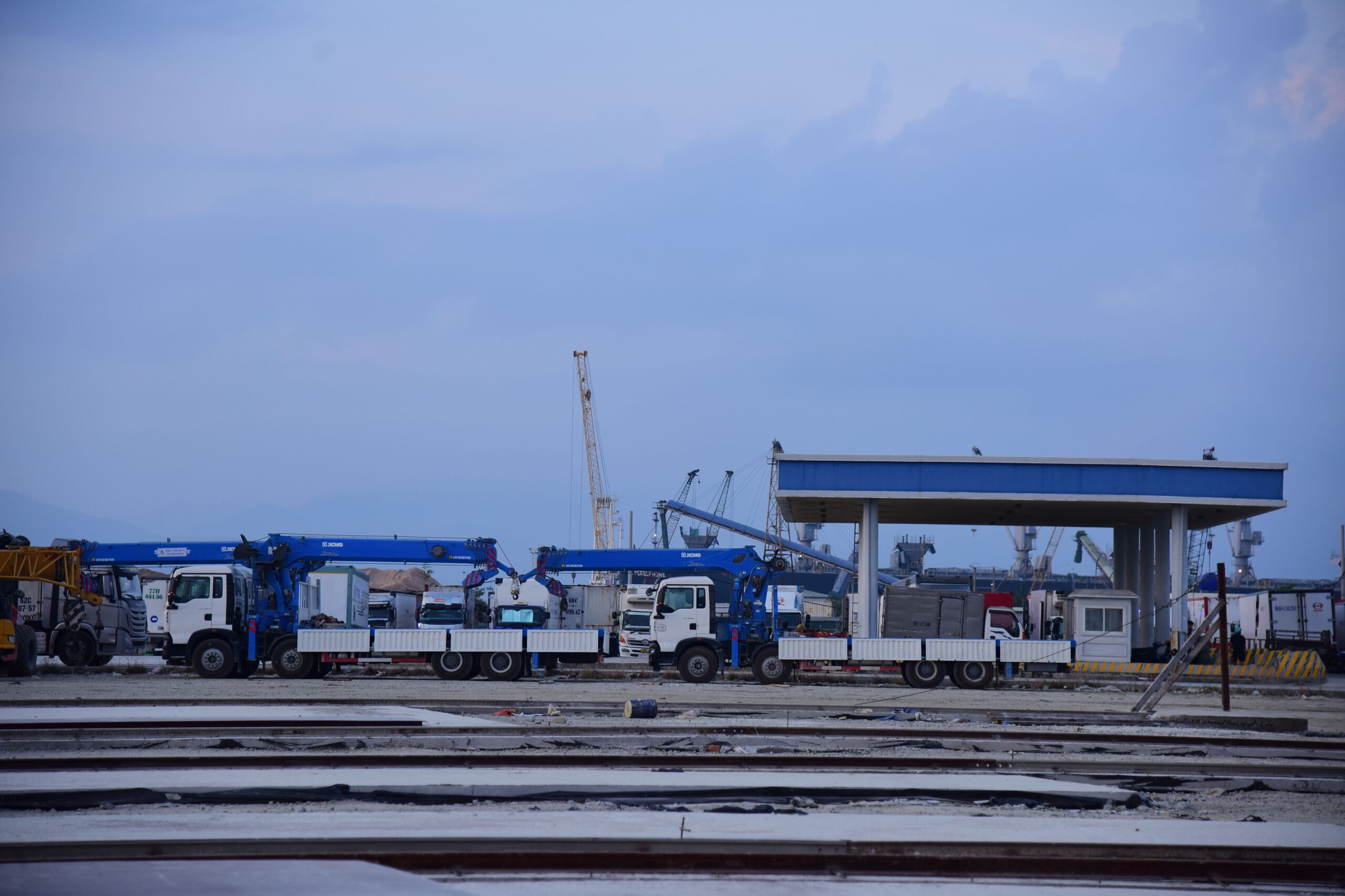 Industrial shipping yard with cranes and trucks where a vehicle speed detection system can monitor site traffic
